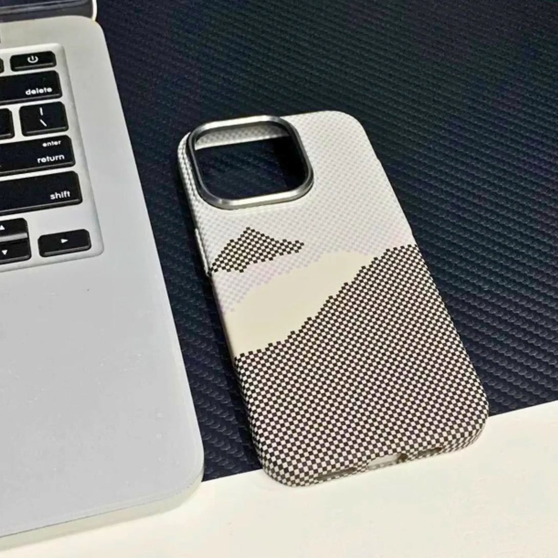Grey and white iPhone case with geometric pattern beside a laptop